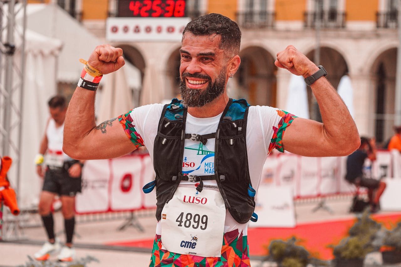 A joyful marathon runner celebrates victory at the finish line outdoors.